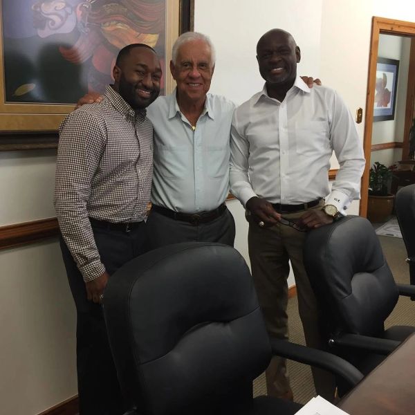 Three men posing happily in an office setting.