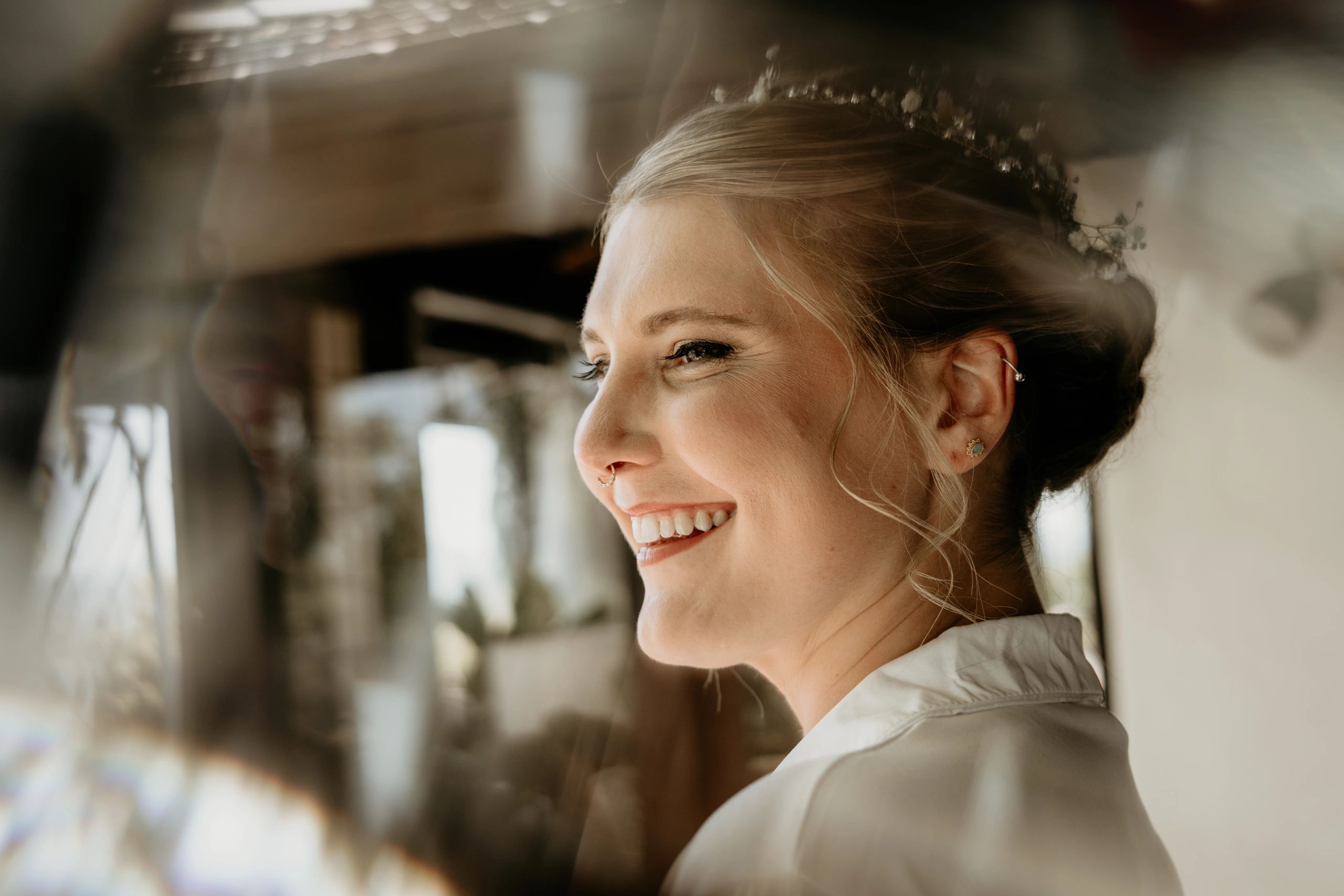 A joyful woman with a floral headpiece smiles warmly.