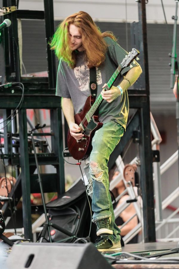 Guitarist with long hair playing on stage.