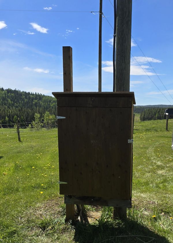 Wooden utility box in a grassy field.