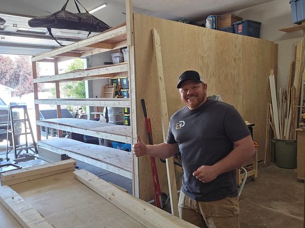 Man giving thumbs up in a woodworking workshop.