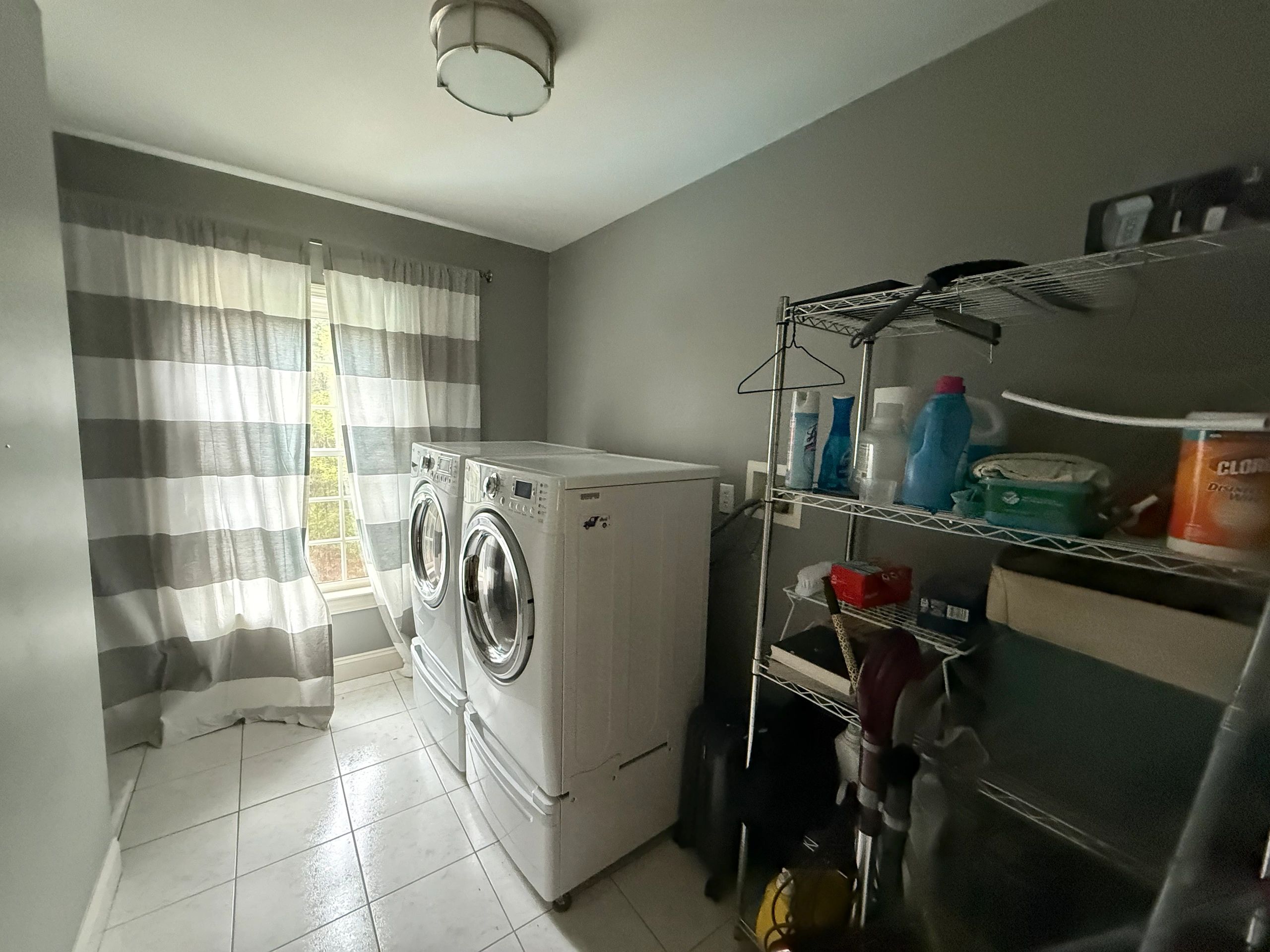 Laundry room with washer, dryer, and storage shelf.