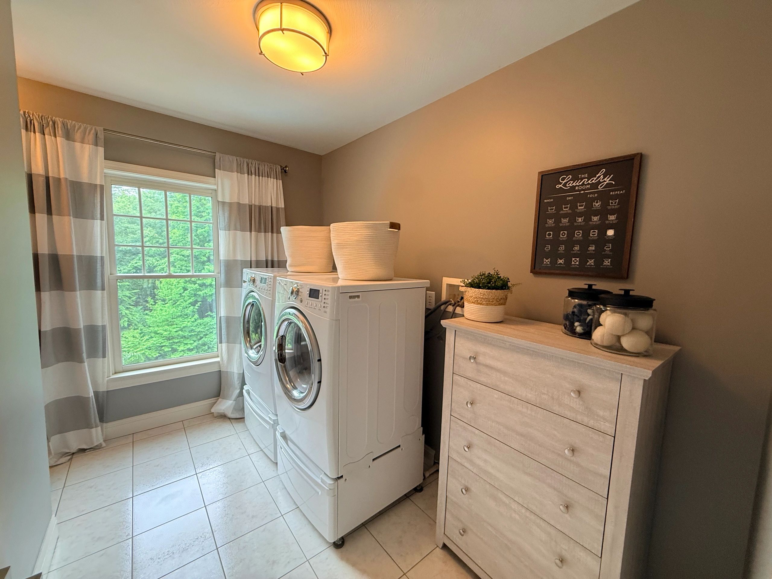 Bright laundry room with washer, dryer, and storage drawers.
