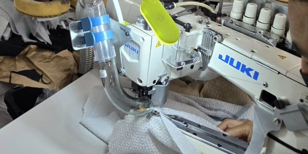 Close-up of a JUKI sewing machine stitching a thick fabric.