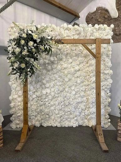 Wooden frame with white floral backdrop and greenery on one side.