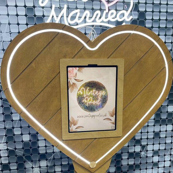Wooden heart-shaped frame with illuminated edge and a tablet inside.