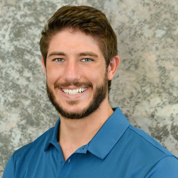 Smiling man with beard in blue shirt.