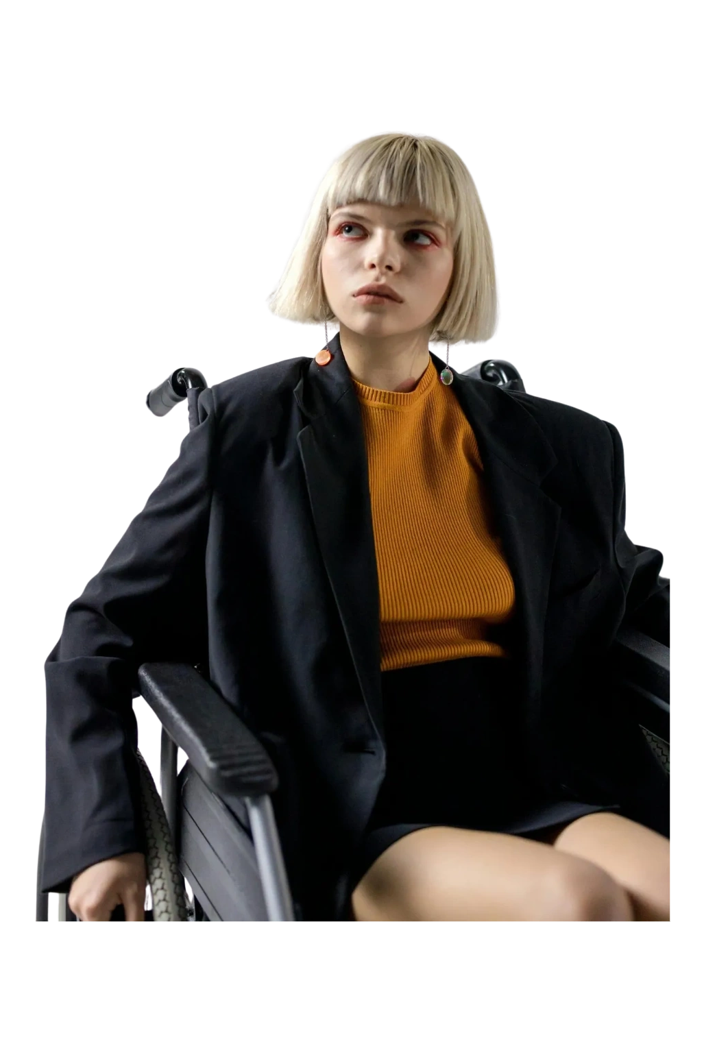 Blonde fashion model with a short bob, using a black wheelchair, wearing an orange jumper