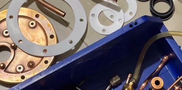 Various metal mechanical parts and fittings organized in blue containers on a surface.