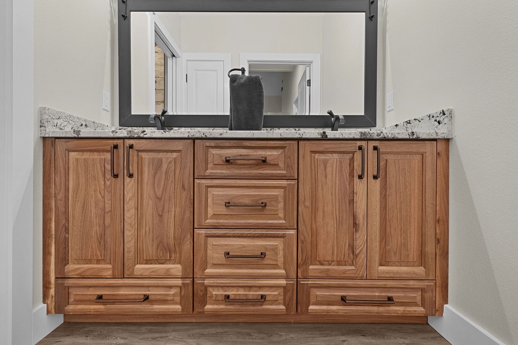 Wooden bathroom vanity with granite countertop and large mirror.