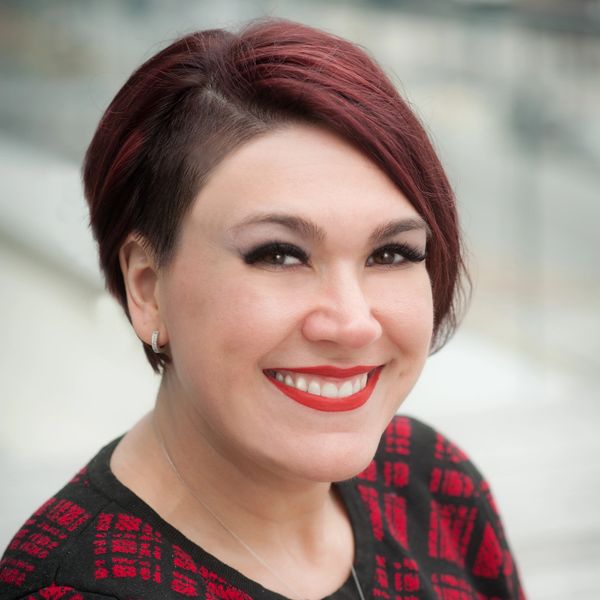 Photo of Alana Goodman with short red hair in a red and black dress.