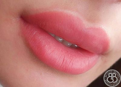 A close-up photo of a woman with lip blush tattoo. 