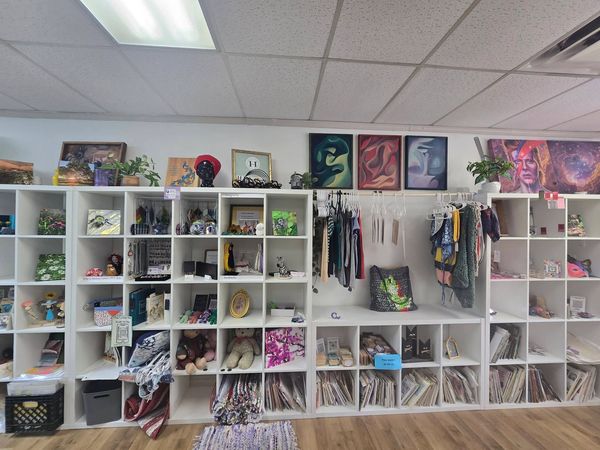 Shelves filled with art, crafts, and clothing in a cozy store.