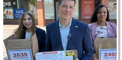 Three people holding boxes with petition signatures.