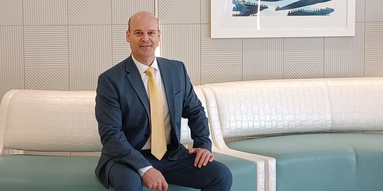 Man in a suit sitting on a modern curved bench in a stylish lobby.