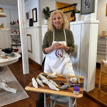 Woman crafting ceramic birds in a cozy workshop.