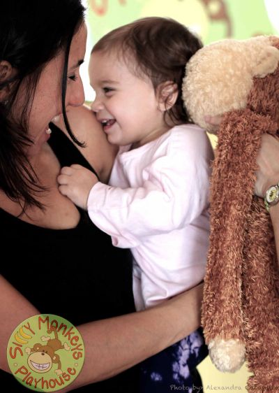 Mother and toddler sharing a joyful moment with a stuffed monkey toy.