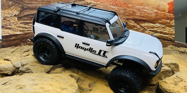 White off-road RC car on rocky terrain.
