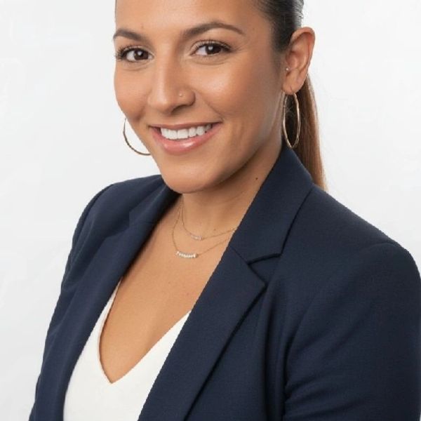 Smiling woman in a navy blazer and white top.