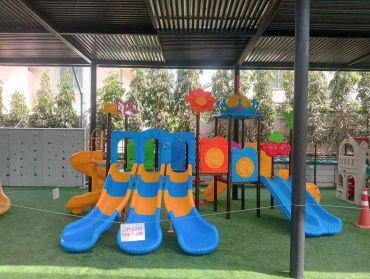 Colorful indoor playground slides under a shaded roof.
