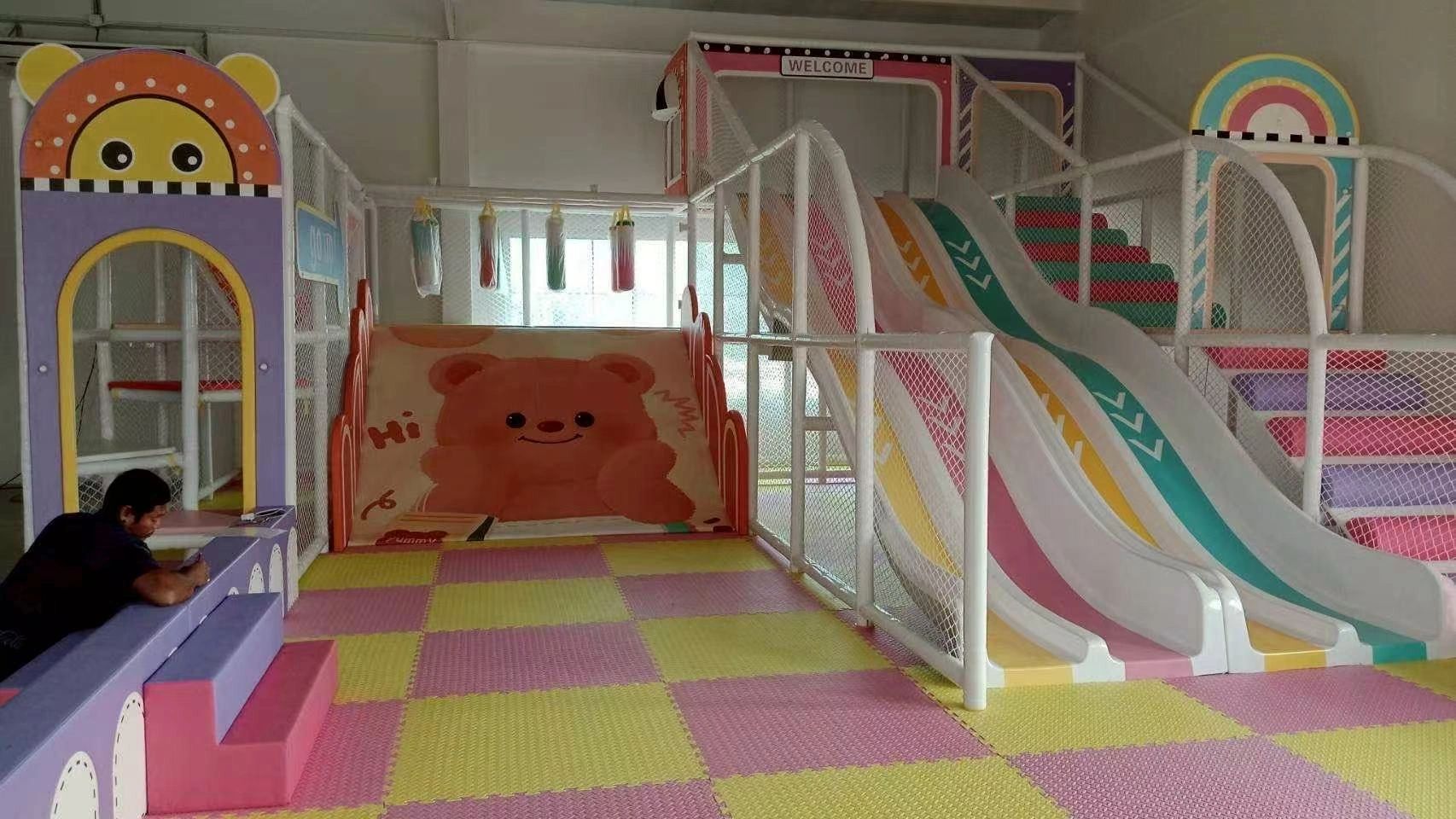 Colorful indoor playground with slides and padded flooring.