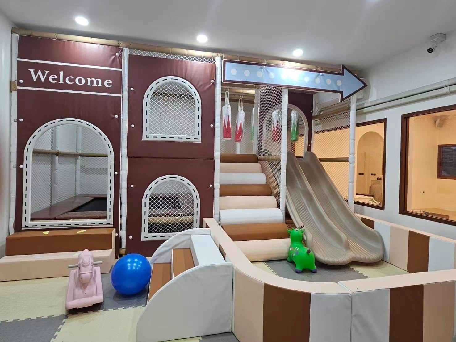 Indoor kids' play area with slides, climbing steps, and soft toys.