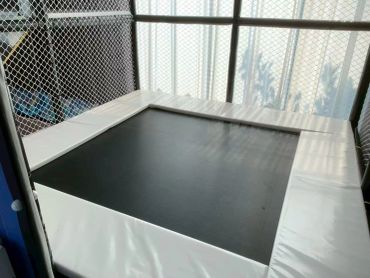 A small indoor trampoline enclosed by a safety net.