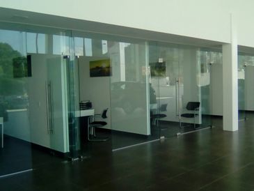 Modern office space with glass-walled meeting rooms and minimalistic furniture.