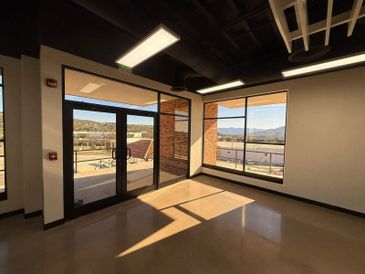 Empty room with large windows and sunlight streaming in.