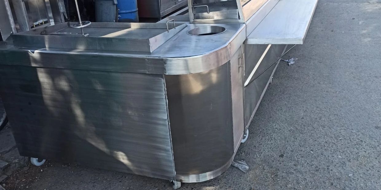 Stainless steel food cart with wheels and foldable side table.