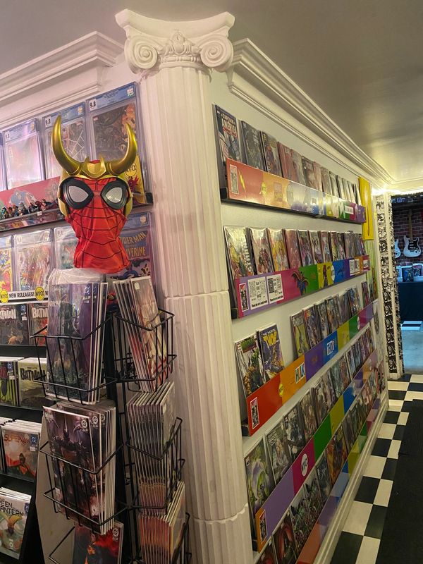 Comic book store corner with colorful displays and a Spider-Man mask with horns.
