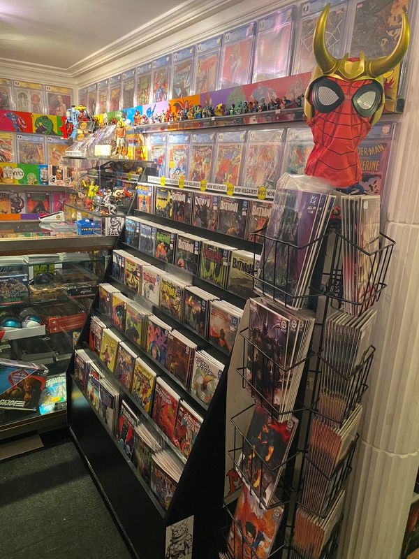 Comic book store aisle filled with comics and collectibles, featuring a Spider-Man helmet with horns.
