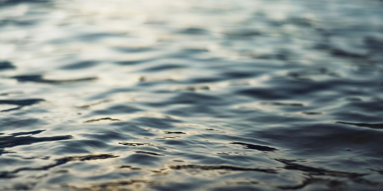 Close-up of gentle water ripples reflecting soft light.