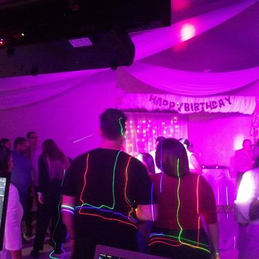 People celebrating a birthday party with neon lights and decorations.