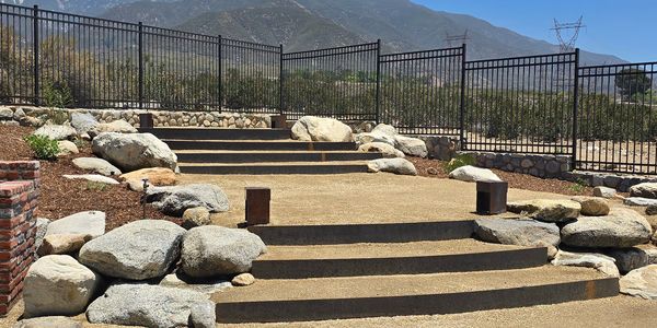 Outdoor stone steps with a metal fence and mountain background.