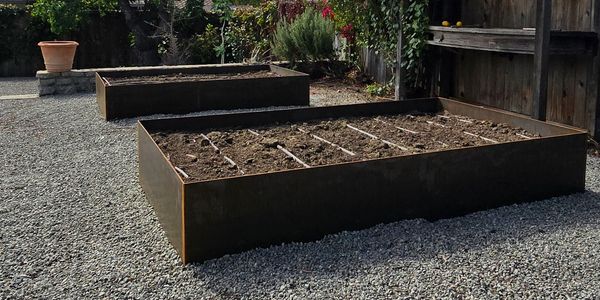 Two empty raised garden beds on gravel.