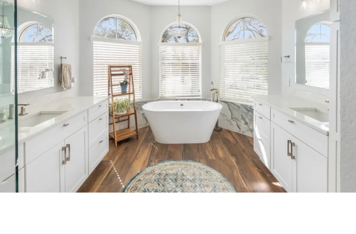 Bright bathroom with white tub and wood floors.
