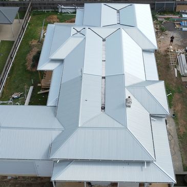 A large house with a complex, light-colored metal roof.