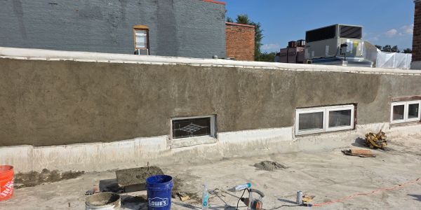 Construction site with cement wall and tools scattered on the ground.