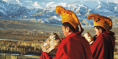 Monks of the yellow hat sect blowing conch shells in a monastery in Zanskar Ladakh