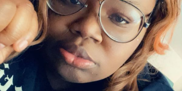 Close-up portrait of a person wearing glasses with a contemplative expression.