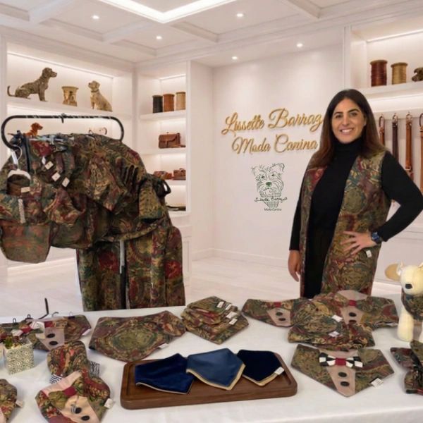 Woman showcasing camo-patterned dog fashion accessories in a stylish boutique.