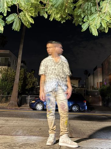 Blurred figure of a person standing on a street at night.