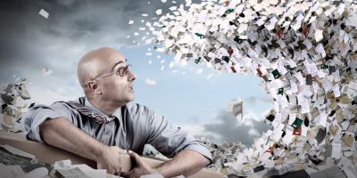Man overwhelmed by a swirling wave of papers.