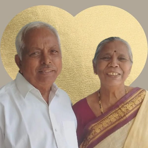 Smiling elderly couple posing with a golden heart backdrop.