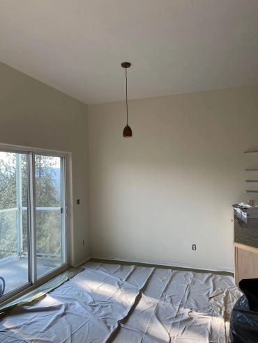 Empty room with covered floor and hanging light fixture.