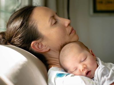 exhausted Postpartum mother resting and holding her baby