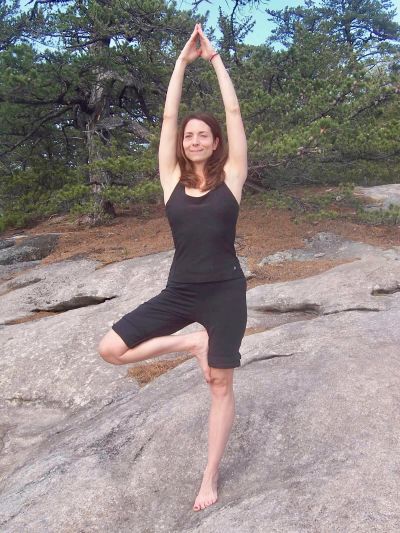 Woman practicing yoga on a rocky terrain.