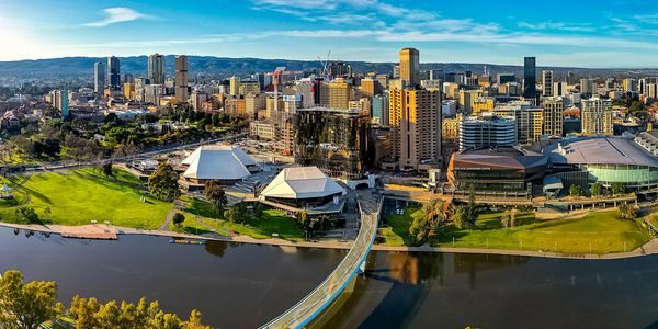 City skyline with a river and bridge under a clear blue sky.