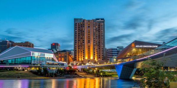 Evening view of Adelaide Convention Centre and city skyline reflected on river.